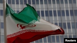 FILE - Caption FILE PHOTO: An Iranian flag flutters in front of the International Atomic Energy Agency (IAEA) headquarters in Vienna, Austria, Sept. 9, 2019. 