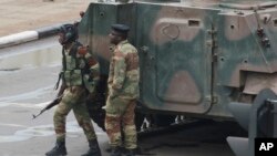 Armed soldiers stand by an armored vehicle on the road leading to President Robert Mugabe's office in Harare, Zimbabwe, Nov. 15, 2017. 