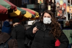 FILE - A woman, who declined to give her name, wears a mask in New York, Jan. 30, 2020. She works for a pharmaceutical company and said she wears the mask out of concern for the coronavirus. "I'd wear a mask if I were you," she said.