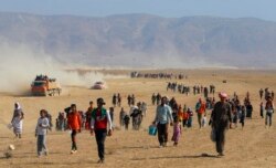 FILE - Displaced people from the minority Yazidi sect, fleeing violence from forces loyal to the Islamic State in Sinjar town, walk toward the Syrian border, on the outskirts of Sinjar mountain, near the Syrian town of Elierbeh of Al-Hasakah Governo