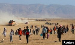 FILE - Displaced people from the minority Yazidi sect, fleeing violence from forces loyal to the Islamic State in Sinjar town, walk toward the Syrian border, on the outskirts of Sinjar mountain, near the Syrian town of Elierbeh of Al-Hasakah Governo