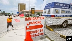 资料照：美国迈阿密市一个移民服务中心的停车场工作人员正为人们提供停车指引。（美联社）