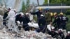 FILE - Rescue workers move a stretcher with recovered human remains at the site of the collapsed Champlain Towers South condo building, in Surfside, Florida, July 5, 2021. 