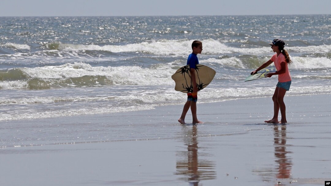 Dua orang anak siap bermain selancar di pantai North Carolina, AS, di mana sudah beberapa kali terjadi serangan oleh hiu di sana (foto: dok).
