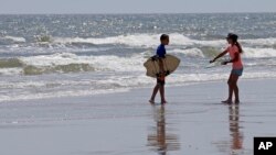 Dua orang anak siap bermain selancar di pantai North Carolina, AS, di mana sudah beberapa kali terjadi serangan oleh hiu di sana (foto: dok).