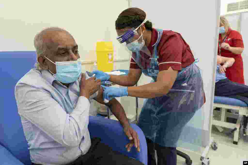 Care home worker Pillay Jagambrun, 61, receives the Pfizer/BioNTech COVID-19 vaccine in The Vaccination Hub at Croydon University Hospital, south London, on the first day of the largest immunization program in the UK&#39;s history, Dec. 8, 2020.