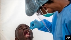 A man opens his mouth for a heath worker to collect a sample for coronavirus testing during the screening and testing campaign aimed to combat the spread of COVID-19 . (AP Photo/Themba)