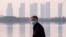 FILE - In this Jan. 30, 2020 file photo, a man wears a face mask as he stands along the waterfront in Wuhan in central China's Hubei Province.