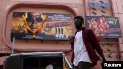 Seorang pria melintasi poster film Bollywood "Sooryavanshi" di luar gedung bioskop di Mumbai, India, 5 November 2021. (REUTERS/Francis Mascarenhas).