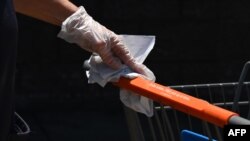 An employee wearing a glove cleans shopping carts at Walmart, July 22, 2020 in Burbank, California. 