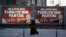 A woman passes a picture of the Turkish Prime Minister Binali Yildirim for the 15th anniversary of AKP party as the sign reads ''The people's voice, Turkey's party, it's now fifteen years old'' in Istanbul, Monday, Aug. 15, 2016.