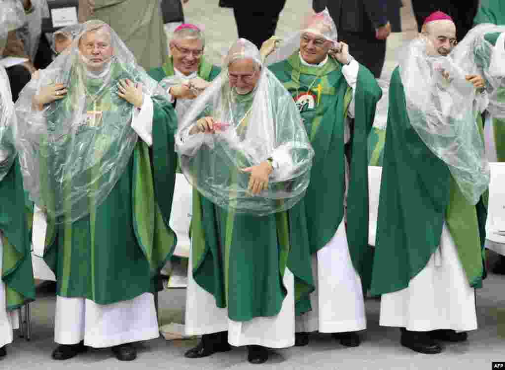 Members of the Catholic clergy put on rain ponchos during a Holy Eucharist celebration conducted by Pope Benedict XVI at the Olympic Stadium in Berlin September 22, 2011. REUTERS/Morris Mac Matzen