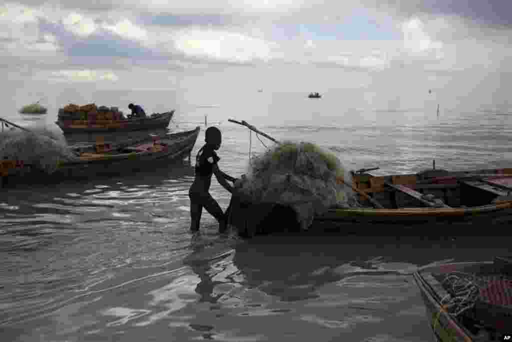 Un niño ayuda a su padre a llevar a la orilla su bote de madera como precaución contra el huracán Irma, en un barrio de Puerto Príncipe, Haití. La tormenta llegará el jueves a Haití. AP Sept. 6, 2017.