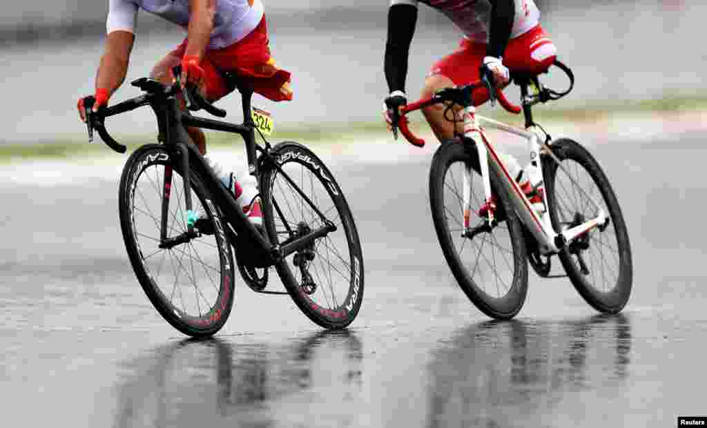 Guihua Liang of China and Shota Kawamoto of Japan compete in the men's cycling road C1-3 at the Fuji International Speedway during the Tokyo 2020 Paralympic Games in Oyama, Japan.