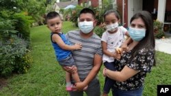 Elbin Sales, left, poses for a photograph with his wife, Yecenia Solorzano and children Jordi and Athena, amid the new coronavirus pandemic in Immokalee, Fla., a poor farm-working town in rural Florida in the throes of an outbreak, June 7, 2020.