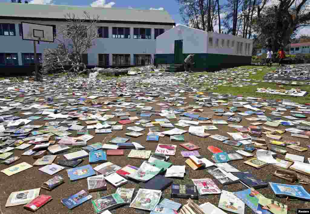 Paul Alexander Hatyay (C), the headmaster, and teacher of Central School, lays out books to dry in the sun after the roof of the school&#39;s library was blown away by Cyclone Pam in Port Vila, the capital city of the Pacific island nation of Vanuatu. &nbsp;