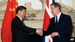 FILE - British Prime Minister David Cameron, right, shakes hands with China's President Xi Jinping, at the UK-China Business Summit in Mansion House, central London, Oct. 21, 2015