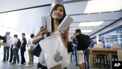 A customer shows her new iPhone 5 at the Apple store in Hong Kong, September 21, 2012.