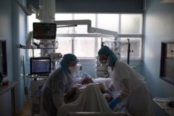 FILE - Healthcare workers assist a COVID-19 patient in the intensive care unit at the Joseph Imbert Hospital Center in Arles, southern France, Apr. 5, 2020.