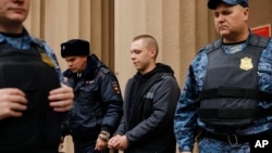 Nikita Zhuravel is escorted by police from a court after a hearing on a treason case in Volgograd, Russia, on Nov. 14, 2024.