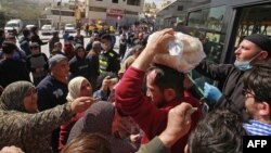 Warga antre membeli roti murah dari mobil milik pemkot di pinggiran Marka di timur Ibu Kota Yordania, Amman, 24 Maret 2020. (Foto: AFP)