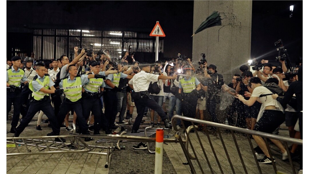 FILE - Police officers use pepper spray during a rally against a proposed extradition law at the Legislative Council in Hong Kong, June 10, 2019.