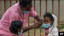 Face masks are placed on children in Antananarivo, Madagascar, Oct. 3, 2017. Authorities in Madagascar are struggling to contain an outbreak of the plague that so far has killed 89 people.