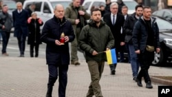 Ukraine's President Volodymyr Zelenskyy, right, and German Chancellor Olaf Scholz walk to a memorial honoring fallen soldiers, in Kyiv, Ukraine, Dec.2, 2024. 