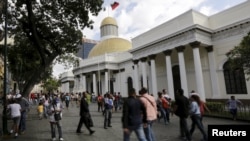 FILE - People walk past the National Assembly building in Caracas, Venezuela.