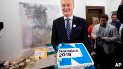 Economist Gitanas Nauseda, a presidential candidate, holds a cake as they celebrate his win in the first round of Lithuania's presidential election in office in Vilnius, Lithuania, early Monday, May 13, 2019.