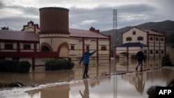 Hombres caminan por una calle inundada de Alora, cerca de Málaga, en Españas después de fuertes lluvias, el 29 de octubre de 2024.