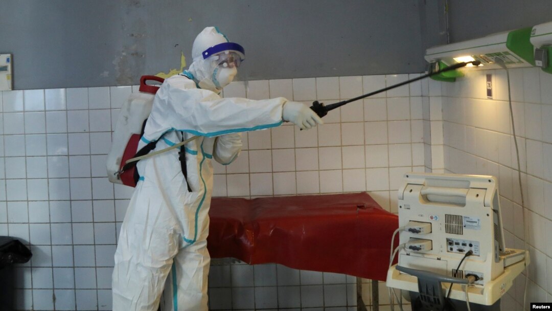 umukozi w'inzego z'ubuvuzi atera umuti wica udukoko twa Ebola mu cyumba.