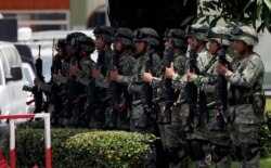 Mexican soldiers present arms as the country's Minister of Defense drives by, in Tapachula, Mexico, June 11, 2019. Mexican officials say they are beginning deployment of 6,000 National Guard troops for immigration enforcement.