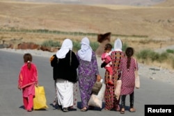 Para perempuan dan anak-anak Yazidi, yang melarikan diri dari kekerasan di kota Sinjar, Irak, berjalan menuju kamp pengungsi setelah mereka kembali memasuki Irak dari Suriah di perbatasan Irak-Suriah di Fishkhabour, provinsi Dohuk, 14 Agustus 2014. (Youssef Boudlal/REUTERS)