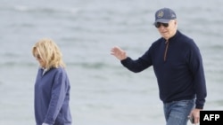 US President Joe Biden waves as he and First Lady Jill Biden as they walk on the beach at Gordons Pond in Rehoboth Beach, Delaware, on November 10, 2024. (Photo by Ting Shen / AFP)