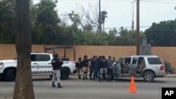 En esta imagen tomada de un video, fuerzas de seguridad mexicanas registran a hombres en un puesto de control, el jueves 2 de mayo de 2024, en Ensenada, México.