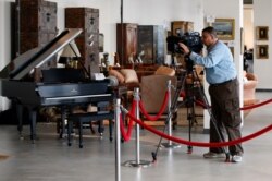 FILE - A photojournalist shoots video of items belonging to Bernard Madoff during a media preview of the U.S. Marshals Service "Madoff II Auction" in the Brooklyn borough of New York, Nov. 10, 2010.