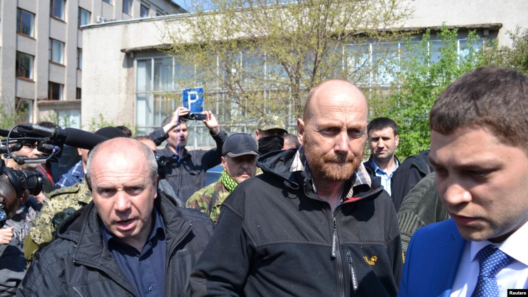 Pengamat OSCE Axel Schneider (tengah) dikawal ketat seusai dibebaskan oleh separatis pro-Rusia yang menahannya sejak bulan lalu di kota Slaviansk, Ukraina Timur (3/5).