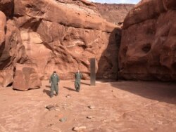Utah Department of Public Safety Aero Bureau and Utah Division of Wildlife Resources crew members walk near a metal monolith they discovered in a remote area of Red Rock Country in Utah, Nov. 18, 2020.