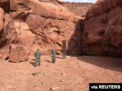 Utah Department of Public Safety Aero Bureau and Utah Division of Wildlife Resources crew members walk near a metal monolith they discovered in a remote area of Red Rock Country in Utah, Nov. 18, 2020.