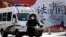 A woman and a police van pass a Chinese government propaganda billboard that reads "China Rule By Law" on a street in Beijing, Dec. 28, 2016. Infuriated by a decision by Beijing prosecutors to drop charges in a high-profile police brutality case, university alumni circles across China mobilized online this week with petition drives, posing to China's government an unusual challenge with its white-collar makeup and swiftly expanding nationwide reach. 