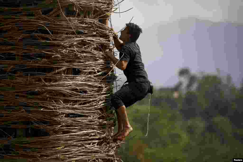 A devotee climbs the chariot of Rato Machhindranath to fix ropes during the chariot festival at Bungamati in Lalitpur, Nepal. Rato Machhindranath is known as the god of rain and both Hindus and Buddhists worship Machhindranath for good rain to prevent drought during the rice harvest season.