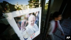 A woman walks by a poster of Pope Francis at the Urakami Cathedral in Nagasaki, southern Japan.