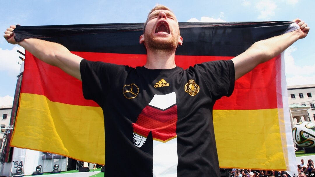 Pemain sepakbola Jerman Per Mertesacker merayakan kemenangan timnya di Piala Dunia dalam upacara dekat Gerbang Brandenburg di Berlin, Jerman (15/7). (AP/Alex Grimm)