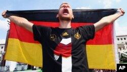 Pemain sepakbola Jerman Per Mertesacker merayakan kemenangan timnya di Piala Dunia dalam upacara dekat Gerbang Brandenburg di Berlin, Jerman (15/7). (AP/Alex Grimm)