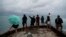People look out over the ocean along Waikiki Beach in a light rain from Tropical Storm Lane, Aug. 25, 2018, in Honolulu.