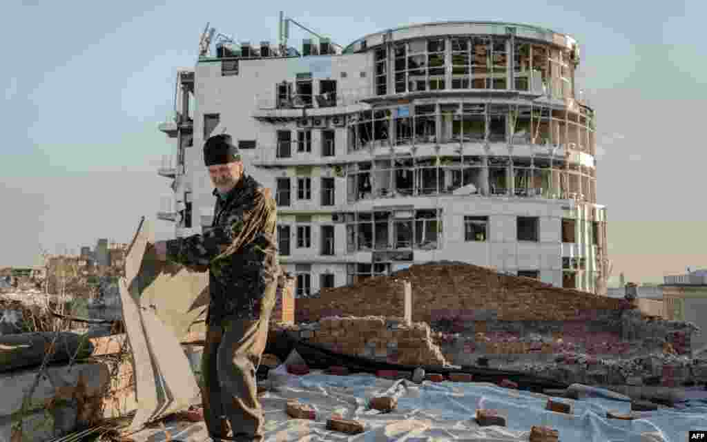 Mykola Hrishyn, 71, removes debris from the roof of a destroyed building where his apartment is located, in Kharkiv, Ukraine, Oct. 26, 2024.