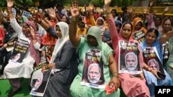 Para aktivis perempuan India membawa potret PM India Narendra Modi dan plakat menuntut Modi agar "tidak hanya diam" atas kekerasan seksual di negara bagian Manipur selama aksi protes di New Delhi Kamis, 20 Juli 2023.