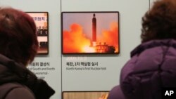 Visitors watch a photo showing North Korea's missile launch at the Unification Observation Post in Paju, South Korea, near the border with North Korea, Dec. 13, 2019. 