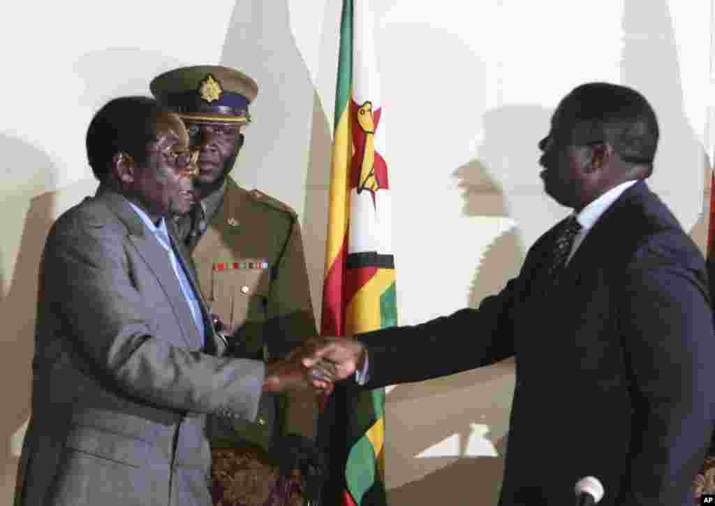 President Robert Mugabe, left, shakes hands with Morgan Tsvangirai, leader of the main opposition in Zimbabwe at the signing of a memorandum of understanding between the two parties.